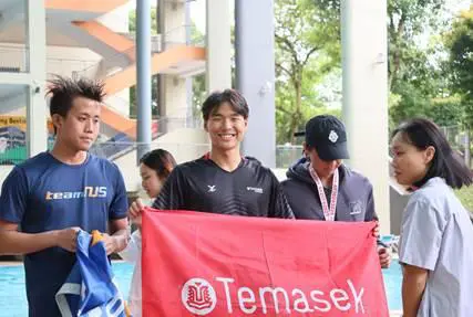 A Temasek Polytechnic student holds up a flag featuring the school logo, symbolising TP pride when representing his CCA. Caption: Zackery Tay was named TP’s 2025 Sportsperson of the Year, a testament to his academic commitment and unwavering team spirit.