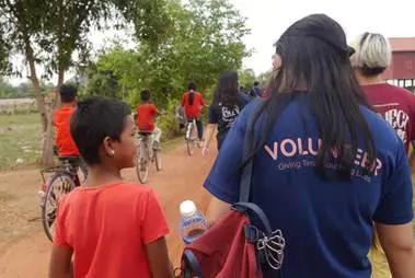 A Temasek Polytechnic student extends community aid in Cambodia on a school trip, symbolising global volunteerism uplift as supported by TP. Caption: On a student trip to Cambodia, Ayuni formed meaningful bonds with local children, deepening her appreciation for community-led agentic care worldwide.