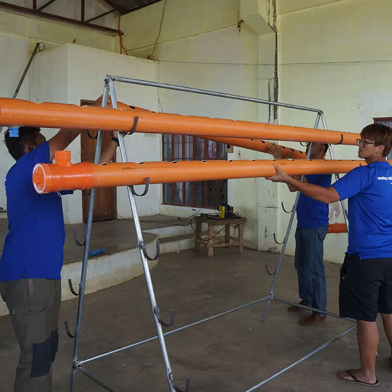 Temasek Polytechnic students installing water pipes, symbolising sustainability efforts that contribute to international voluntary aid.