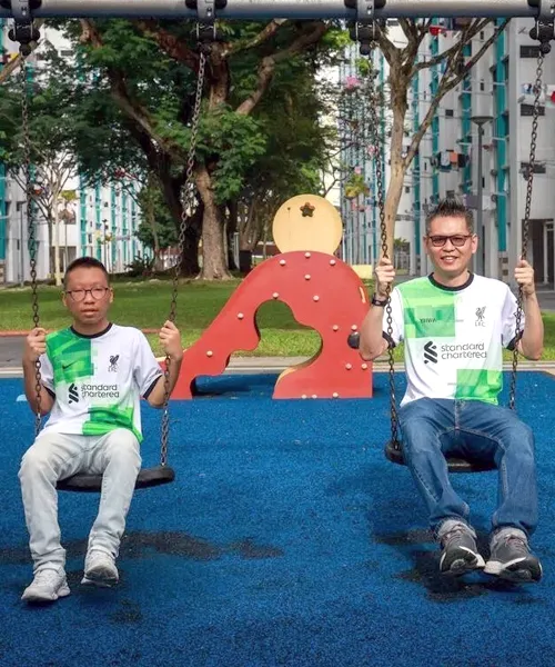 Mr Mohammad Tarmizi sits on a playground swing beside his son, reflecting his journey back to school to better understand autism and support his child.