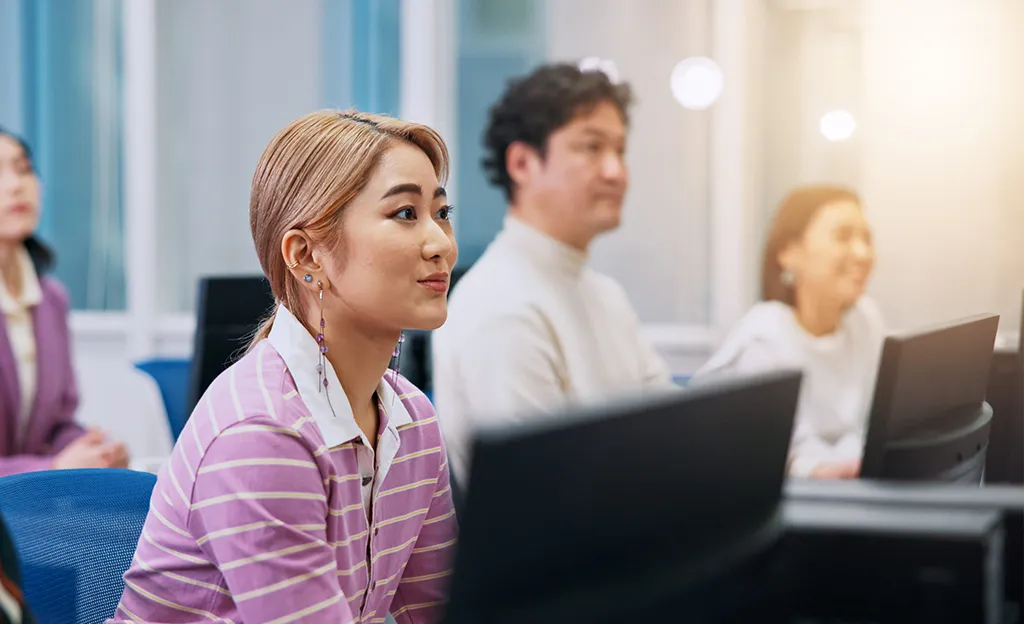 Adult learners developing artificial intelligence and information technology skills in a modern classroom.