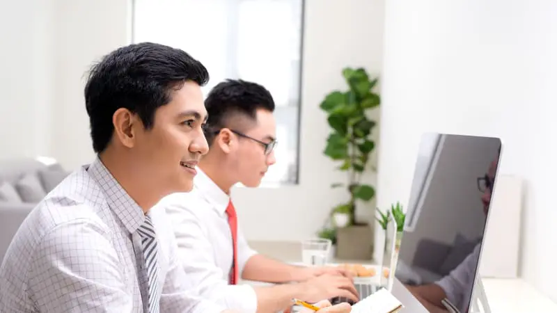 Two corporate professionals in an office setting, each working on their own tasks, symbolising independent work and study. Caption: Temasek Polytechnic’s dynamic curriculum is designed for accessibility for every demographic.